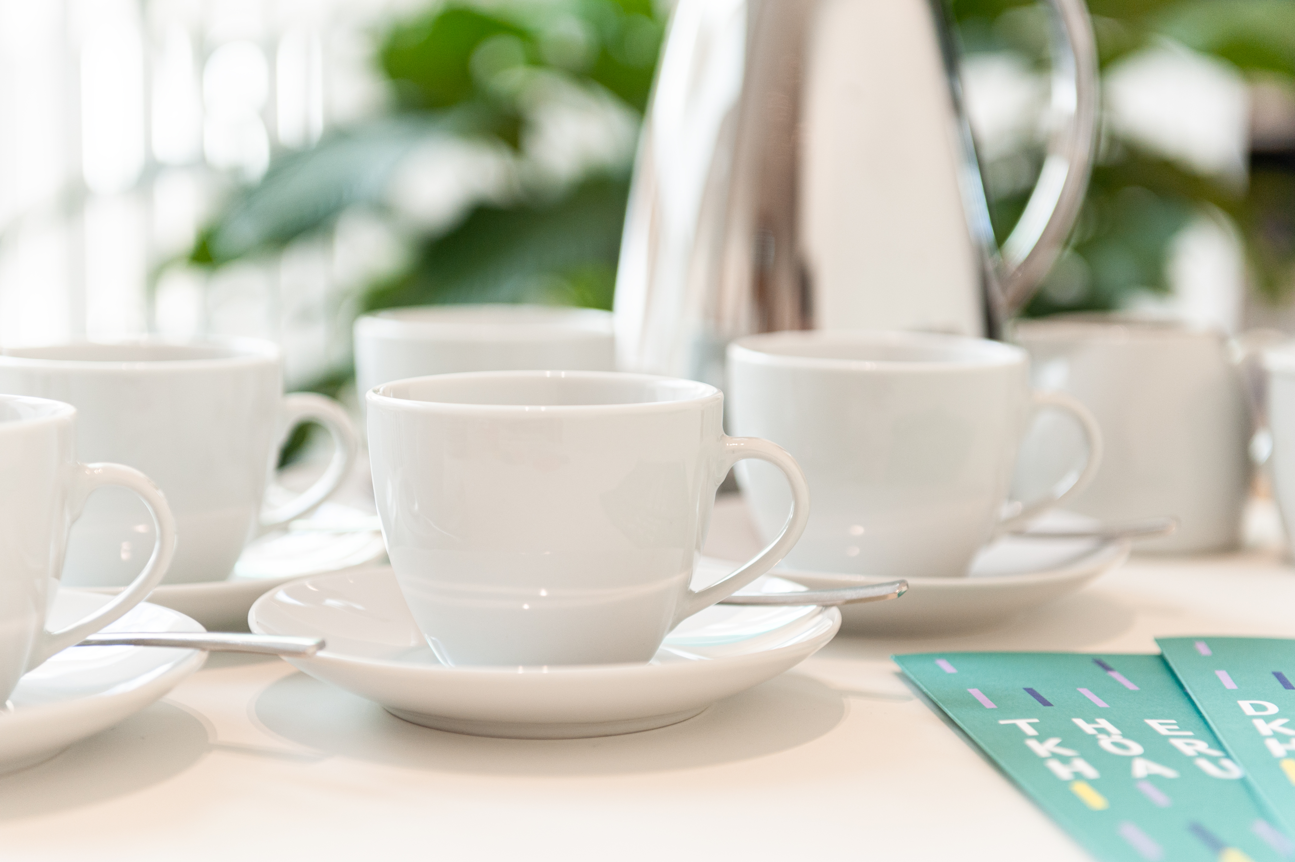 Einige weiße Kaffeetassen, verteilt auf einem Tisch.