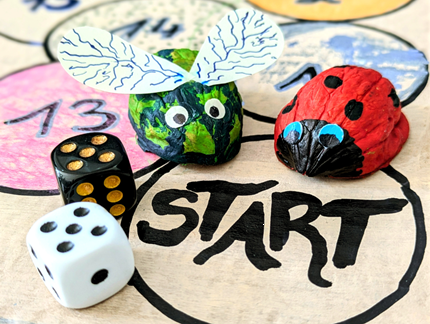 Auf dem Bild stehen angemalte Walnussschalen als Käfer-Figuren auf dem selbstgebastelten Spielfeld.